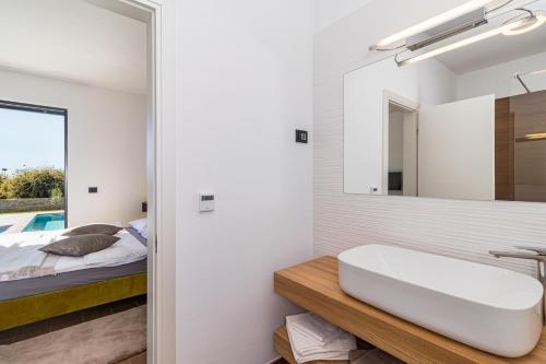 a bathroom with a sink and a bed and a mirror at Villa Sabina in Višnjan