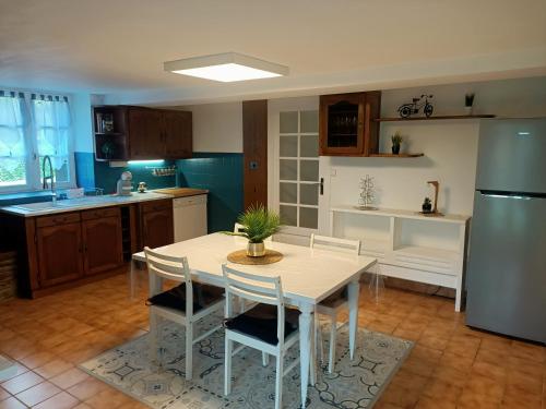 a kitchen with a table with chairs and a refrigerator at Gîte de Soulou in Aramits