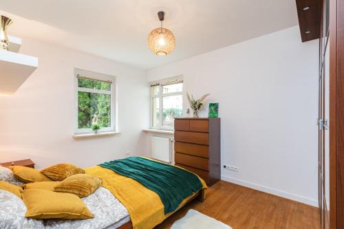 - une chambre dotée d'un lit avec des oreillers jaunes et verts dans l'établissement SuperApart Wilanowska 7, à Varsovie