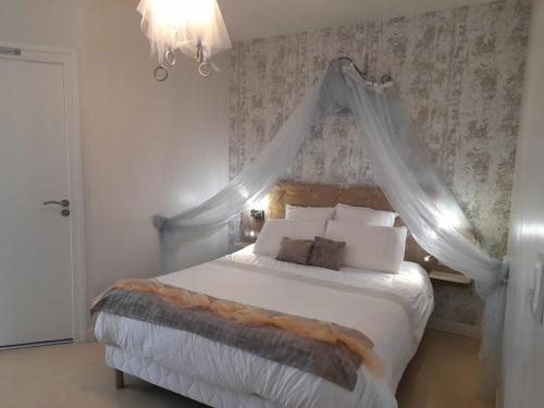 ein Schlafzimmer mit einem weißen Bett mit Baldachin in der Unterkunft La maison du Bonheur in Saint-Bernard