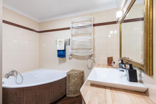 La salle de bains blanche est pourvue d'une baignoire et d'un lavabo. dans l'établissement SuperApart Wilanowska 7, à Varsovie