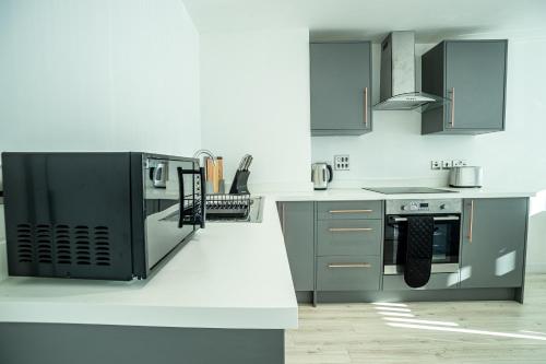a kitchen with stainless steel appliances and gray cabinets at Modern Luxe 1 & 2 Bed Apts near Granby Plaza by Sojo Stay in Leicester