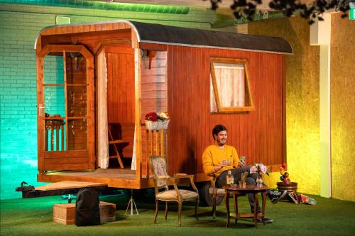 a woman sitting in front of a tiny house at Outside Inn in Amsterdam