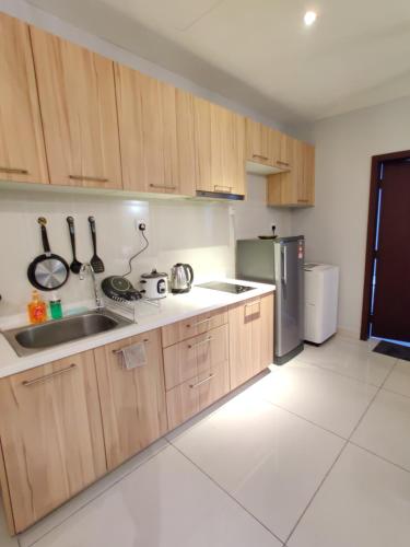 新山的住宿－Ksl D'Esplanade Studio Apartment's 2，厨房配有木制橱柜和不锈钢冰箱。