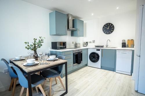 a kitchen with blue cabinets and a table with chairs at Modern Luxe 1 & 2 Bed Apts near Granby Plaza by Sojo Stay in Leicester