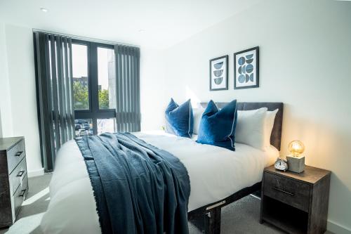 a bedroom with a large bed with blue pillows at Modern Luxe 1 & 2 Bed Apts near Granby Plaza by Sojo Stay in Leicester