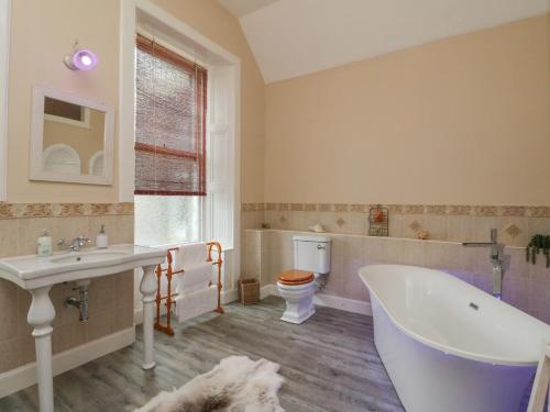 a bathroom with a tub and a sink and a toilet at Woodside House in Arbroath