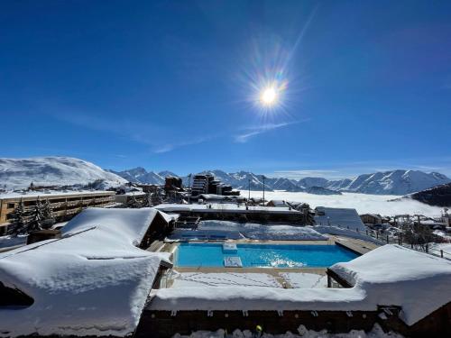 a resort with a swimming pool covered in snow at Superbe Studio avec vue exceptionnelle in L'Alpe-d'Huez