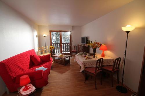 a living room with a red couch and a table at Appartement Adélaïde in Le Hohwald