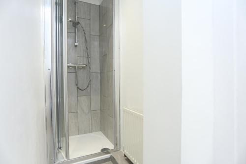 eine Dusche mit Glastür im Bad in der Unterkunft Cosy Room with en-suite bathroom and shared kitchen in Thamesmead