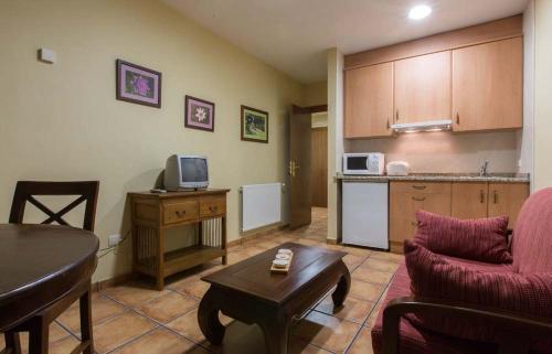 a living room with a couch and a table and a kitchen at Apartamentos Villa de Cabrales in Arenas de Cabrales