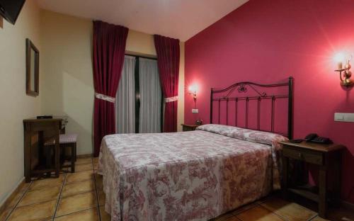 a bedroom with a bed and a pink wall at Apartamentos Villa de Cabrales in Arenas de Cabrales