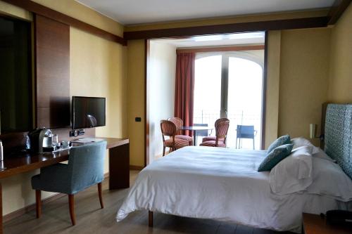 a hotel room with a bed and a desk and a television at Il Porticciolo in Laveno-Mombello
