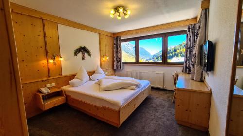 1 dormitorio con 1 cama, TV y ventana en Apart Garni Romantica en Galtür