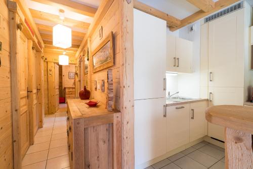 kuchnia z białymi szafkami i drewnianą ścianą w obiekcie Comme un chalet, appartement à la montagne w mieście Saint-Gervais-les-Bains