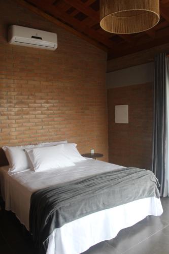 a bedroom with a large bed with a brick wall at Pousada Tabaty in Delfinópolis