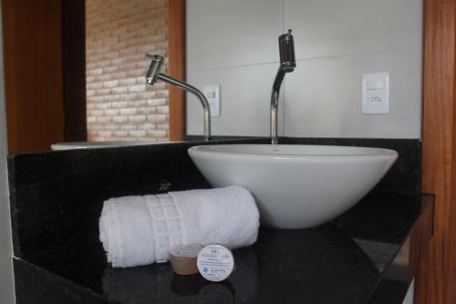 a bathroom with a bowl sink on a black counter at Pousada Tabaty in Delfinópolis