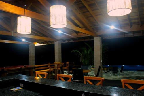 a dining room with tables and chairs and lights at Pousada Tabaty in Delfinópolis