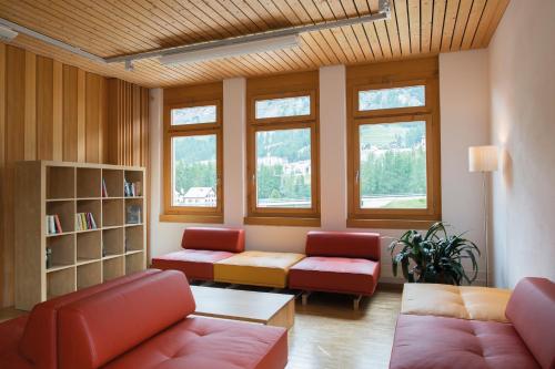 a living room with red furniture and windows at Pontresina Youth Hostel in Pontresina