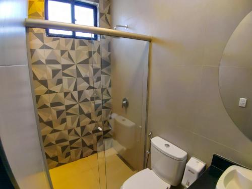 uma casa de banho com um WC e uma cabina de duche em vidro. em Motel Caribe em Belo Horizonte