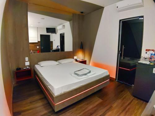 a bedroom with a large bed and a kitchen at Motel Caribe in Belo Horizonte