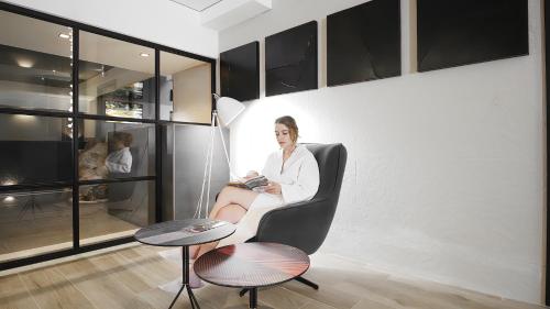 a woman sitting in a chair reading a book at Tskaltubo Hotel Prometheus in Tskaltubo