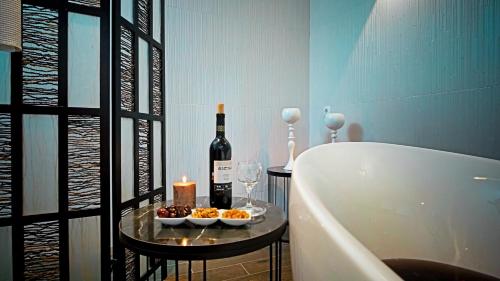 a bathroom with a tub and a bottle of wine and candles at Tskaltubo Hotel Prometheus in Tskaltubo