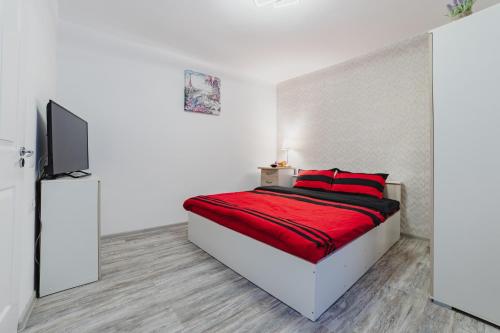 Cette chambre comprend un lit avec des draps rouges et une télévision. dans l'établissement Studio Central Poarta Schei, à Braşov
