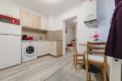 une cuisine avec un lave-linge, une table et des chaises dans l'établissement Studio Central Poarta Schei, à Braşov