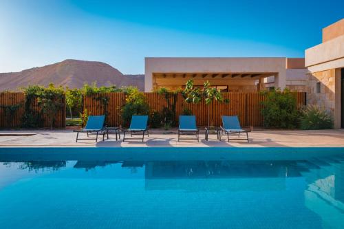 un grupo de sillas sentadas junto a una piscina en The Valley Resort, en Riad