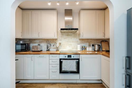 Biała kuchnia z białymi szafkami i urządzeniami w obiekcie MPL Apartments - Watford The Junction Short-Term Rentals - 2bed-FREE PARKING w mieście Watford