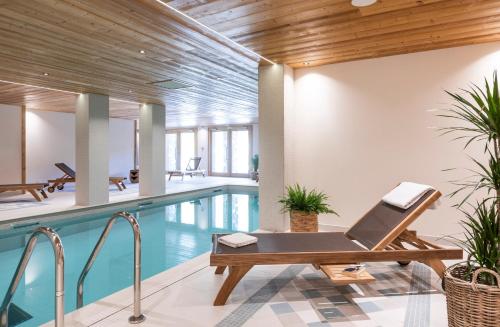 - une piscine intérieure avec un banc à côté d'une piscine dans l'établissement Chalet Hôtelier LES EQUINOXES - VAL D'ISERE, à La Daille