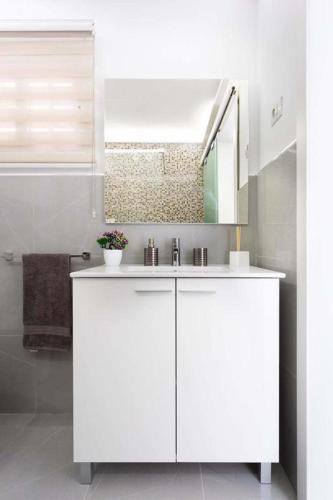 a white bathroom with a sink and a mirror at Manuda Luxury Apartment in Caleta De Fuste