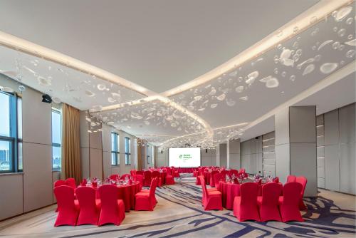 a conference room with red chairs and a screen at Holiday Inn Fuyang by IHG in Fuyang