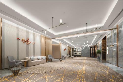 a lobby with a couch and chairs in a building at Holiday Inn Fuyang by IHG in Fuyang