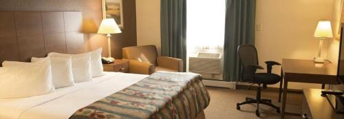 a hotel room with a bed and a desk at Magnuson Grand Pioneer Inn and Suites in Escanaba