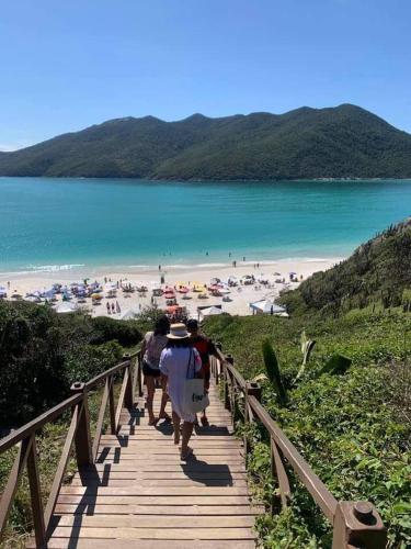 a group of people walking down a boardwalk to a beach at apartamento de frente para o mar com linda area de lazer in Arraial do Cabo