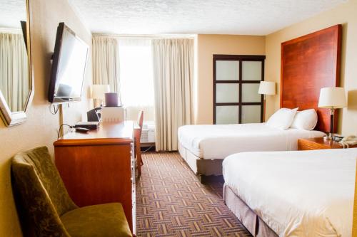 a hotel room with two beds and a desk at Wyndham Garden Medicine Hat Conference Center in Medicine Hat