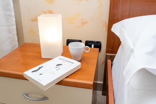 a bedside table with a cup and a book at Contaldi House in Nocera Superiore
