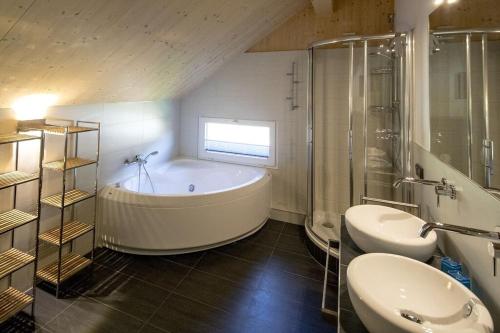 een badkamer met een bad, 2 wastafels en een douche bij Wellness Chalet Bell a Mur in Murau