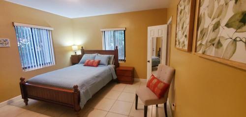 a bedroom with a bed and a chair and two windows at Royal Poinciana Stay in Miami