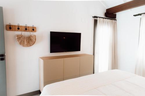 a bedroom with a bed and a tv on a wall at Naatooh Guest Houses in Florianópolis