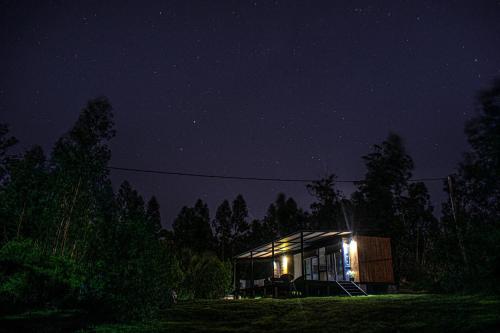 una pequeña cabaña en el bosque por la noche en Agua y Manto, en La Pedrera