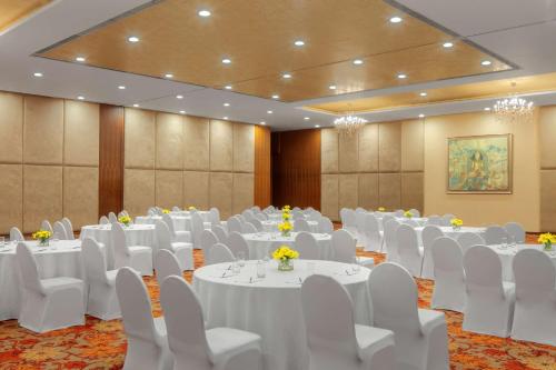a banquet hall with white tables and white chairs at Radisson Blu Plaza Hotel Hyderabad Banjara Hills in Hyderabad