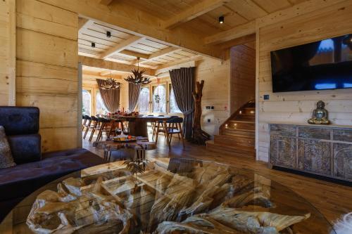 a living room with a table and a fireplace at Bajkowa Chata 3 Magiczne Domki Jacuzzi in Murzasichle