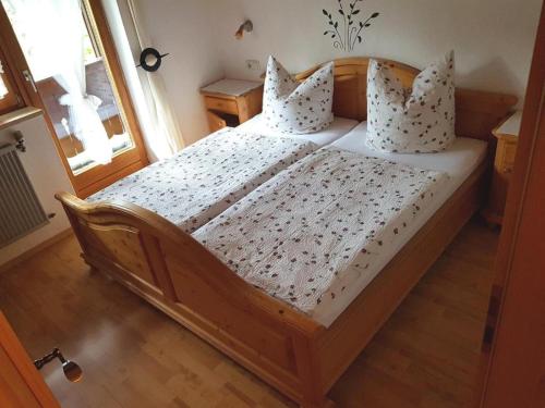 - une chambre dotée d'un lit en bois avec des draps et des oreillers blancs dans l'établissement Ferienwohnung Baumgart, à Schönau am Königssee