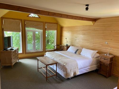 um quarto com uma cama, uma televisão e janelas em Casa Ayacara em Frutillar