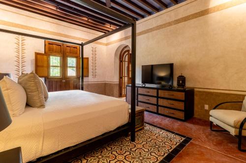 a bedroom with a bed and a tv and a chair at Hacienda San Antonio Hool in Mérida