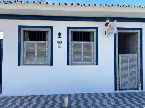 a white building with two windows and a door at Pousada Cores da Passarela - Sob nova direção in Porto Seguro