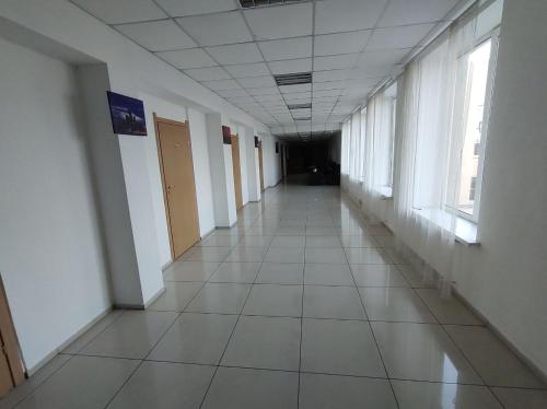 an empty hallway in a building with white floors and windows at Отель Меридиан in Zolotonosha